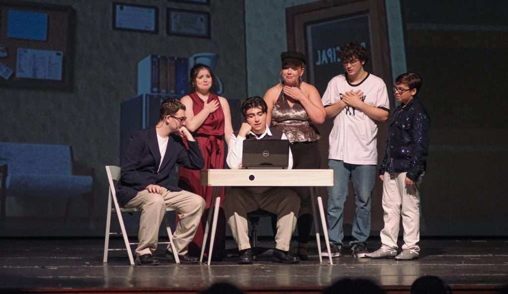 A group of people of all ages on a stage, showcasing their talents through Apple Tree Arts theatre programs.